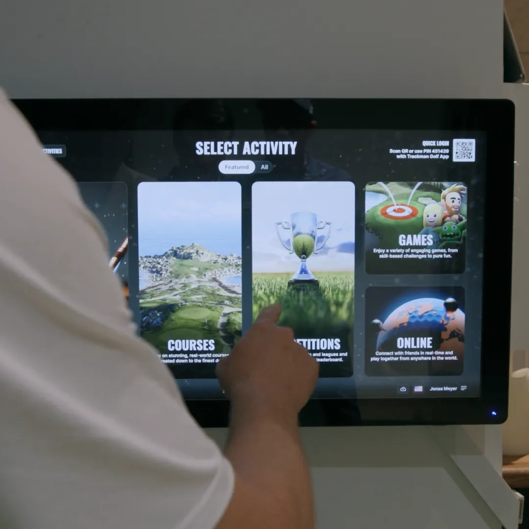 Person interacting with a touchscreen displaying options for courses, competitions, and games, with a finger pointing to "competitions."