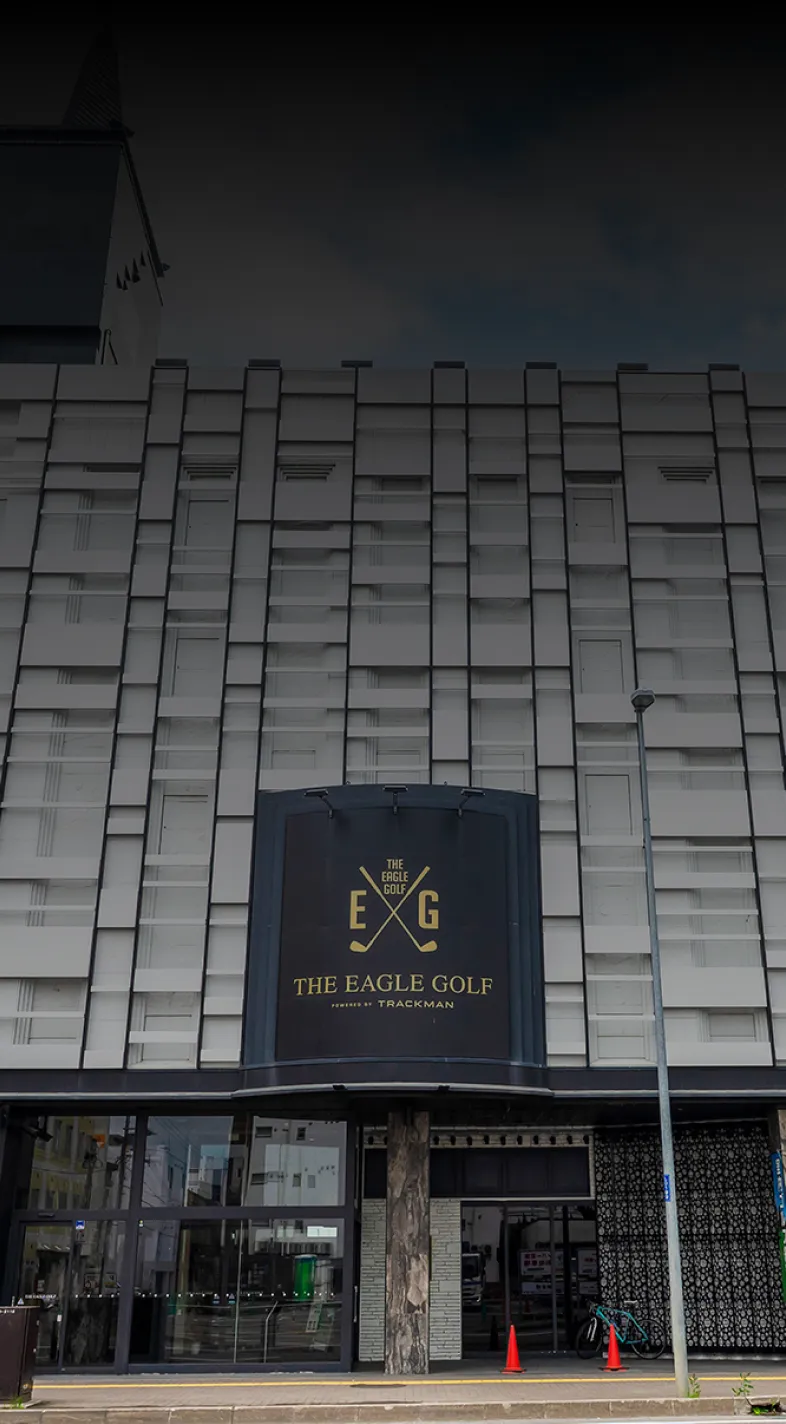 Facade of The Eagle Golf building with a modern geometric design and signage. A tree is visible on the right side.
